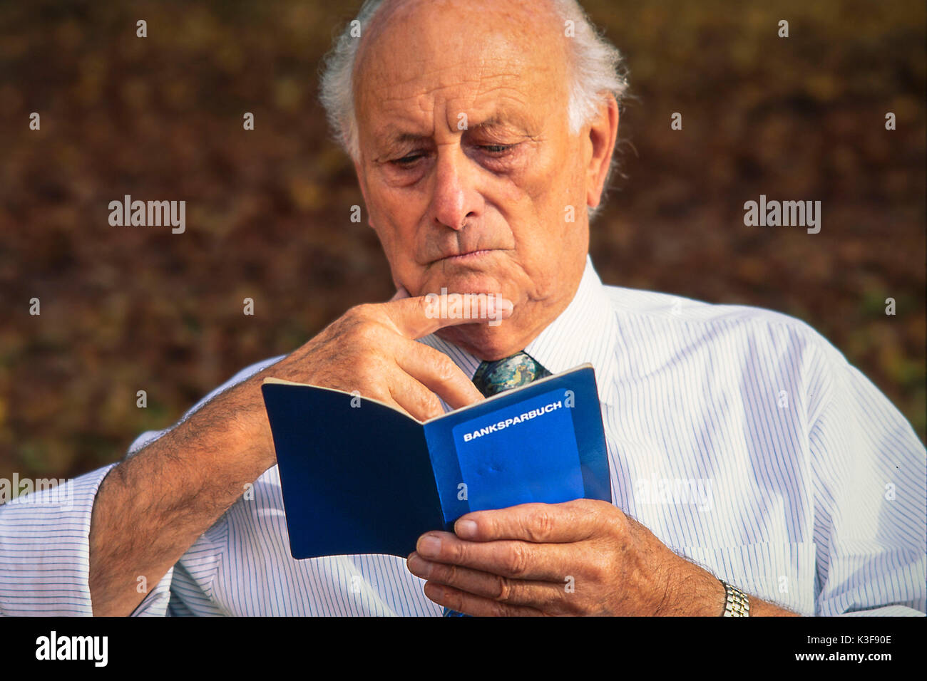 Senior guarda nel suo bankbook Foto Stock