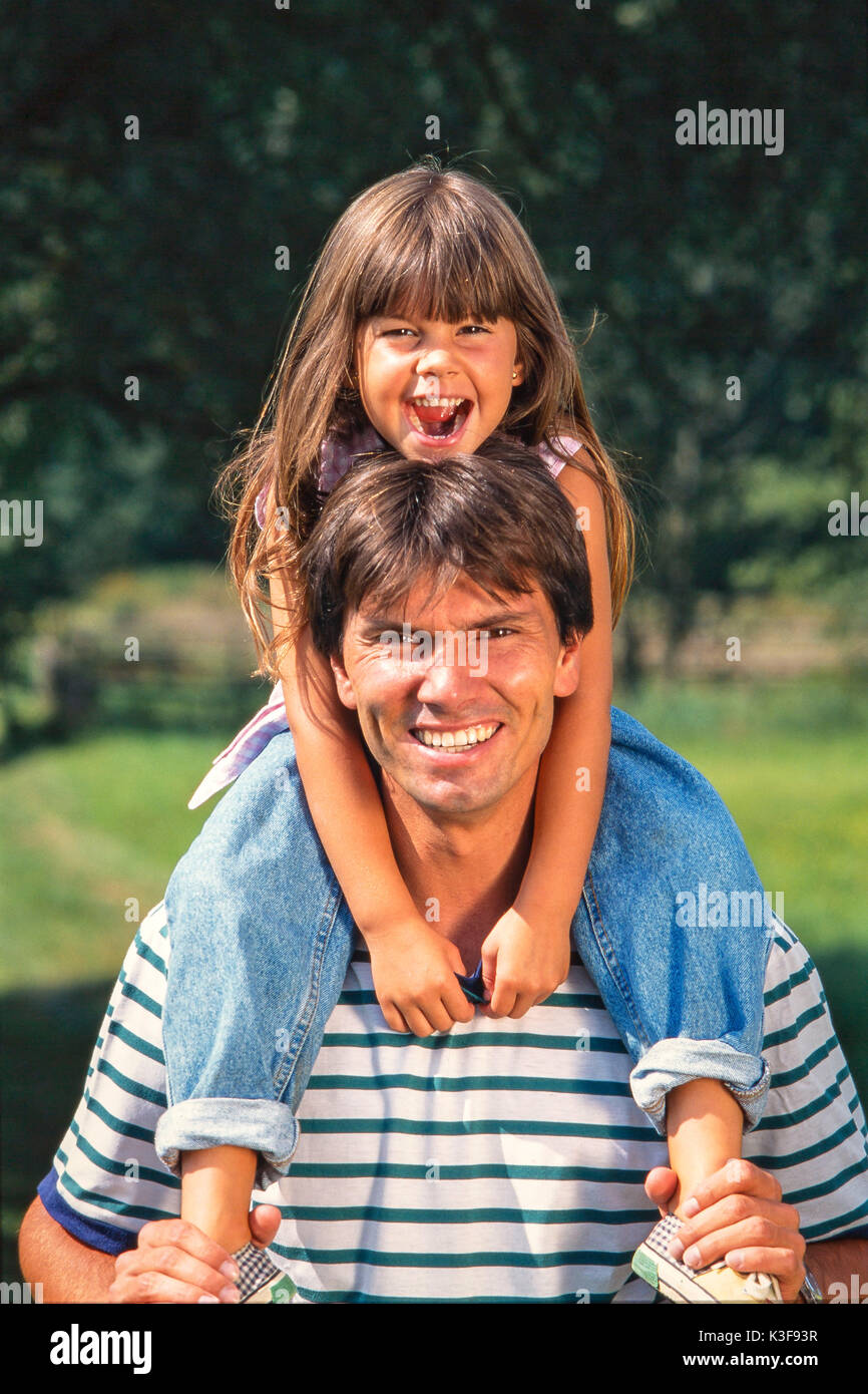 Padre porta a ridere figlia marrone con i peli lunghi sulle spalle Foto Stock