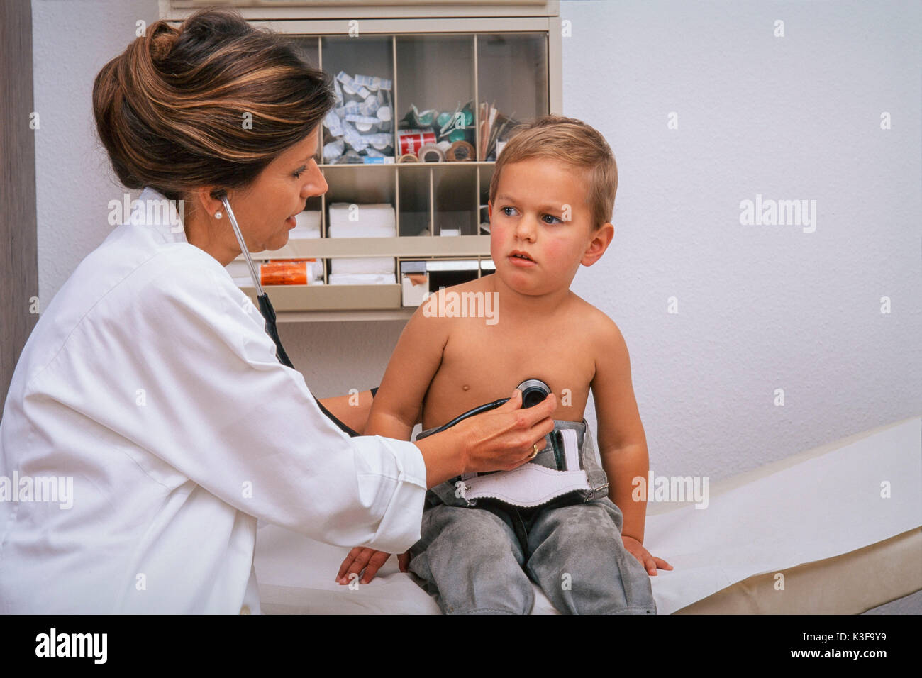 Medico esamina piccolo ragazzo in pratica chiudere lo stetoscopio Foto Stock