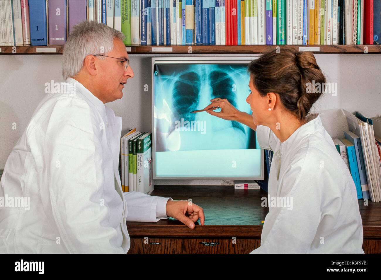 Medico e dottore di sedersi di fronte a raggi X Immagine e fare una diagnosi Foto Stock