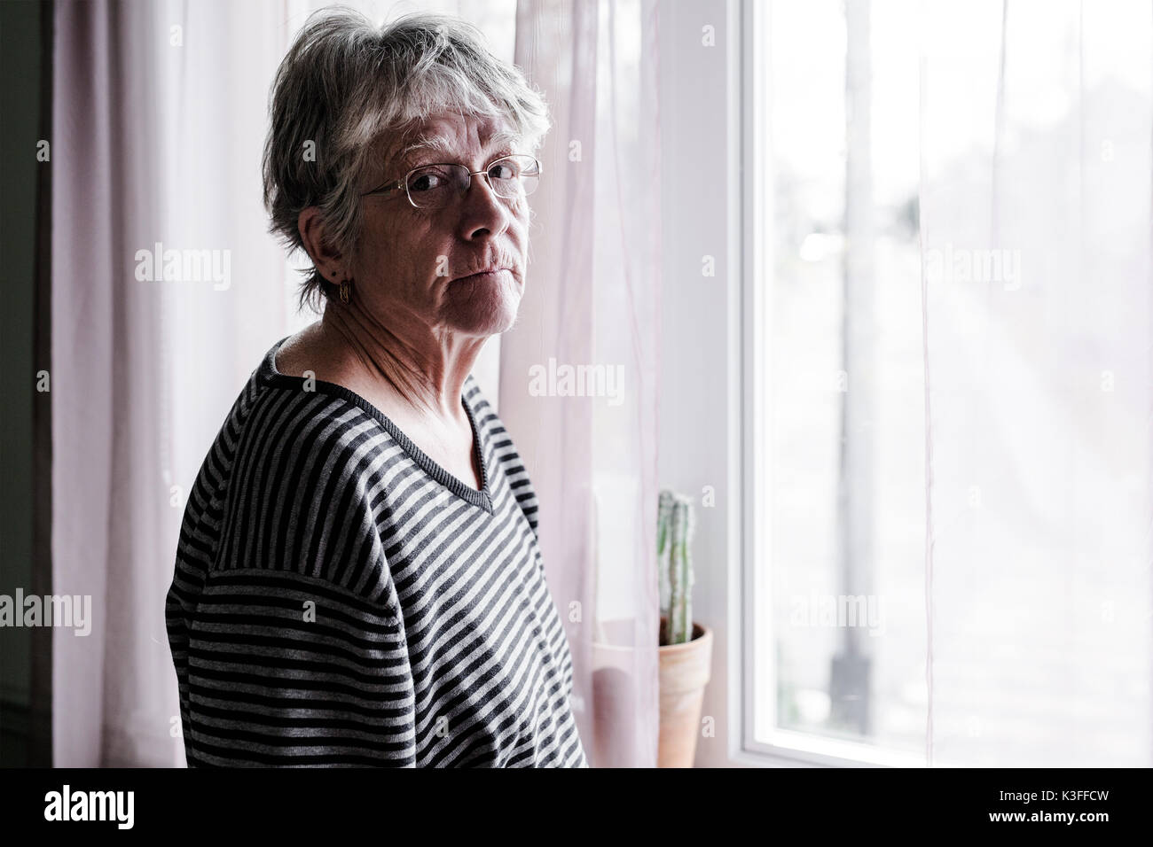 Preoccupato senior donna a casa il taglio molto male Foto Stock