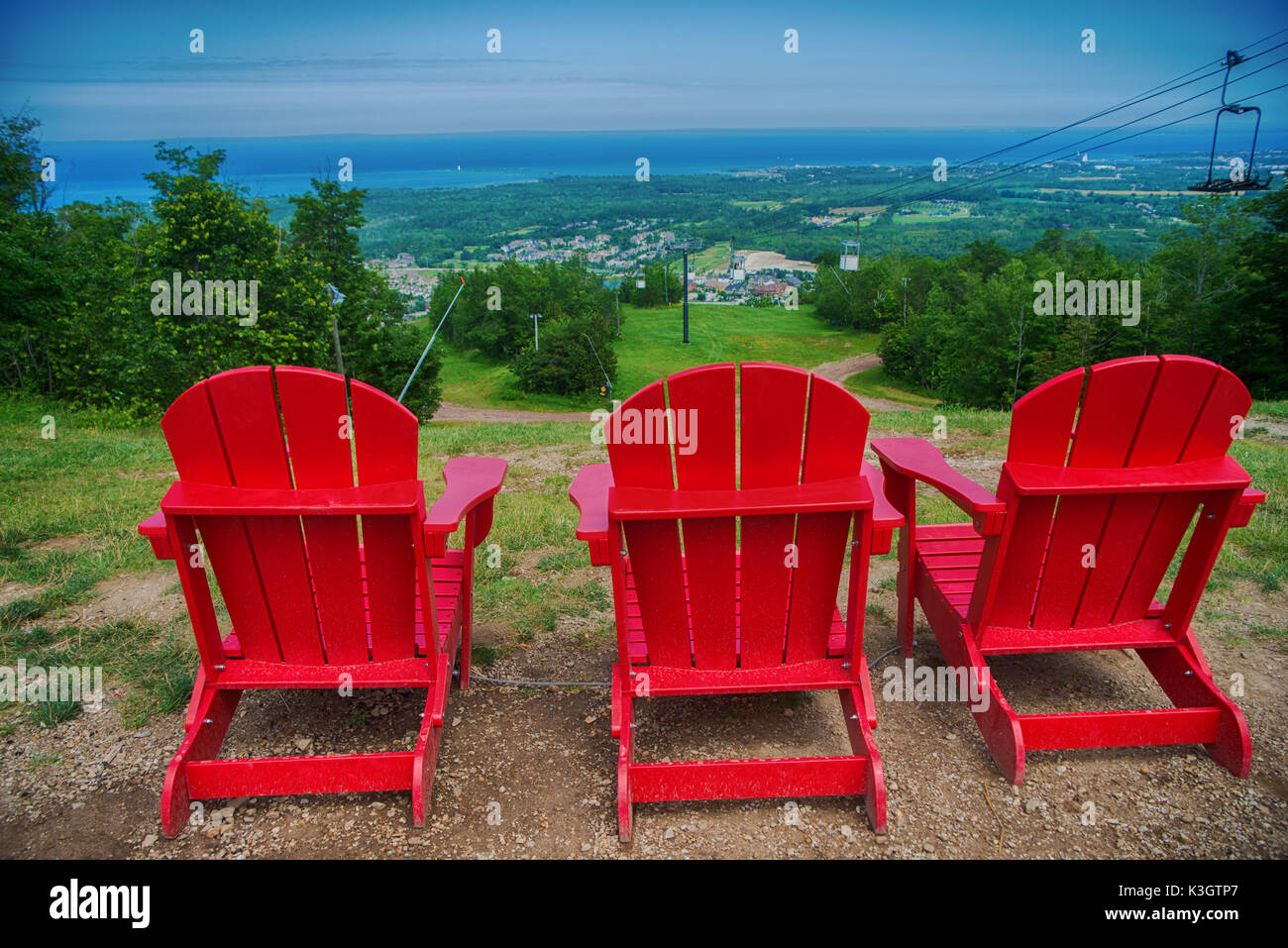 Vista di 3 rosso di muskoka sedie a Blue Mountain Resort e villaggio durante l'estate in Collingwood, Ontario Foto Stock