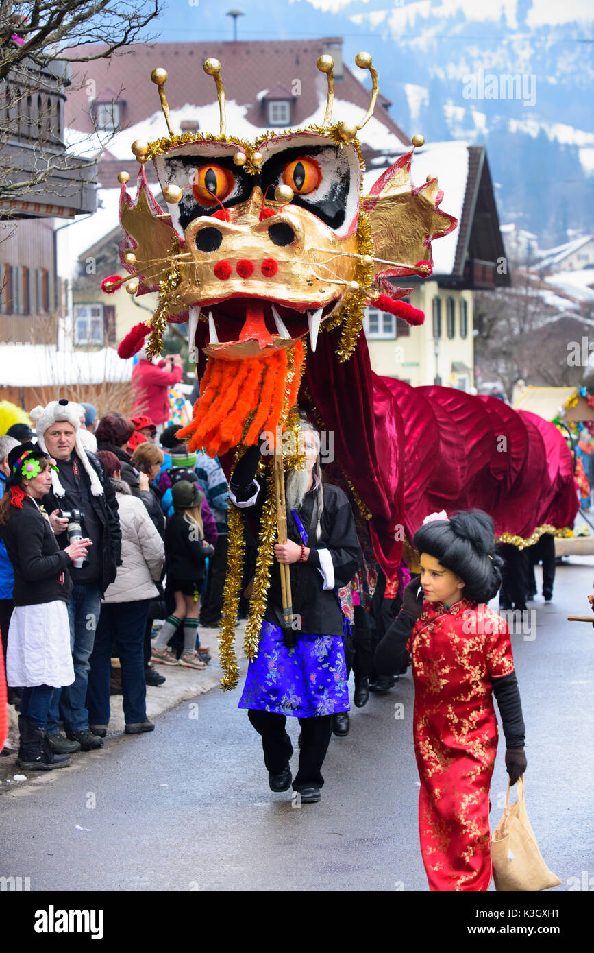 Sfilata di Carnevale sulla strada alta di Bad Hindelang su domenica di carnevale con molte testimonianze artistiche maschere, come per esempio dragone cinese Foto Stock