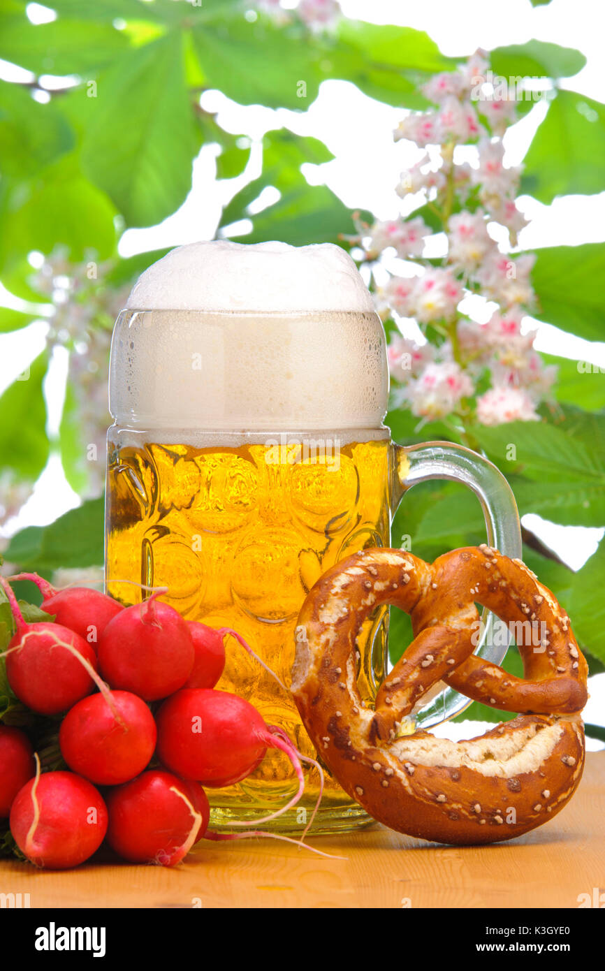 La birra bavarese mug con birra, pretzel e ravanelli nella parte anteriore di una castagna Foto Stock