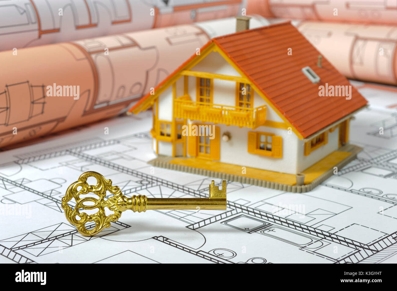 Modello di casa, dell'architetto e piano casa dorata chiave come un icona per costruzione chiavi in mano Foto Stock