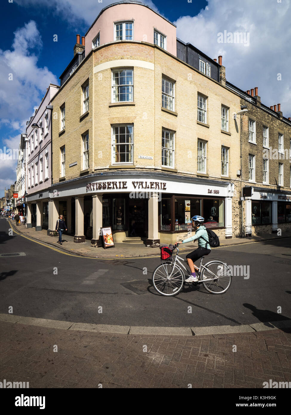 Cambridge Shopping - un ciclista passa Patisserie Valerie sull'angolo di una fila di negozi in Bridge Street, centro di Cambridge Regno Unito Foto Stock