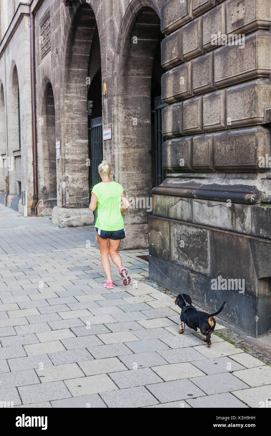 In Germania, in Baviera, Monaco di Baviera, Donna Jogging con piccolo cane sul piombo Foto Stock