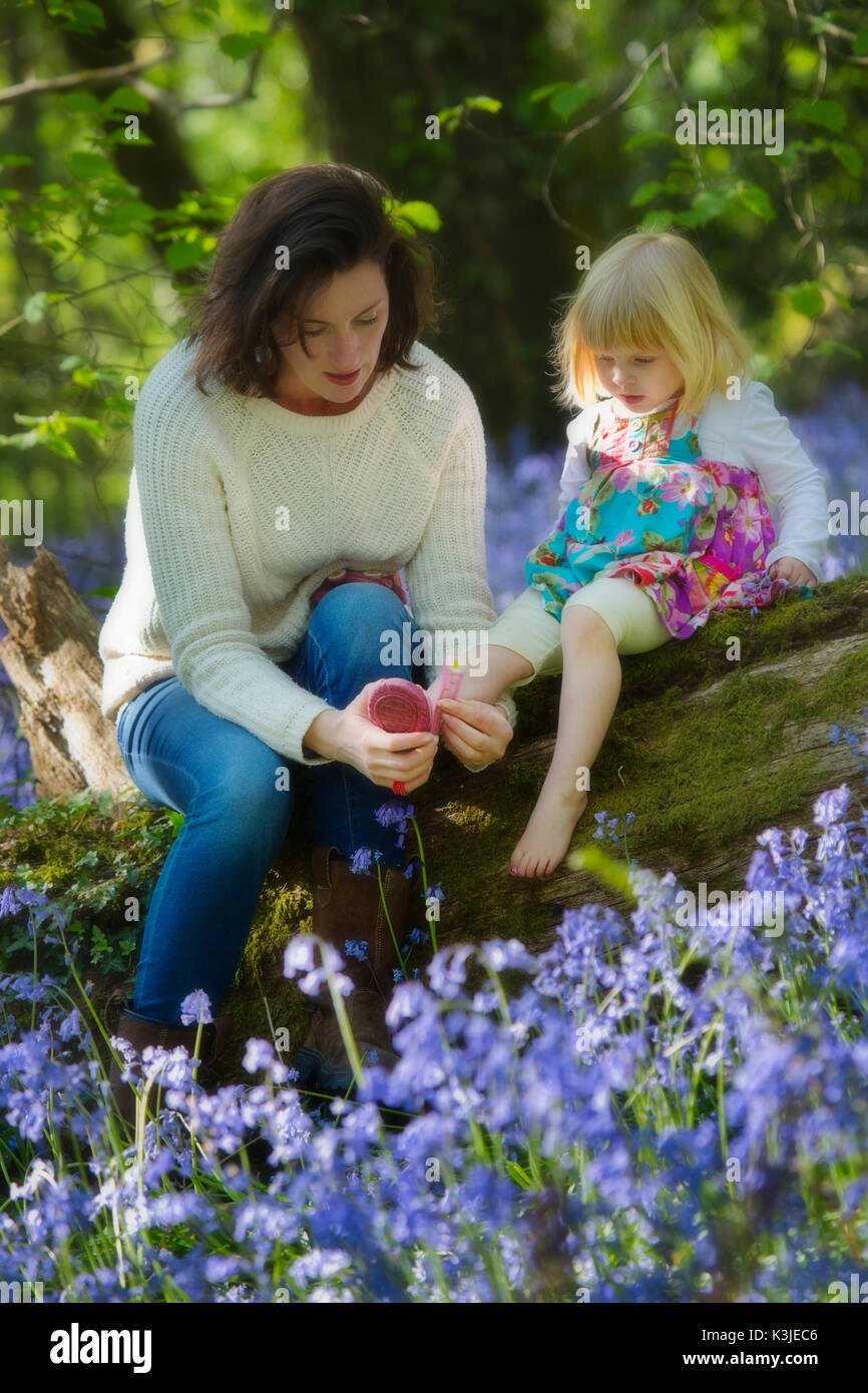 Una giovane madre con il suo bambino in una bluebell wood nel Devon, Inghilterra REGNO UNITO Foto Stock