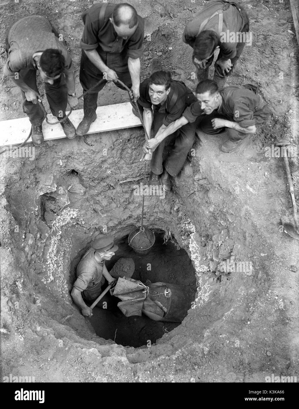 Lavoro pericoloso! Un agente di smaltimento delle bombe che sta scavando una bomba tedesca inesplosa a Londra 1943 Explosive Ordnance Disposal Foto Stock