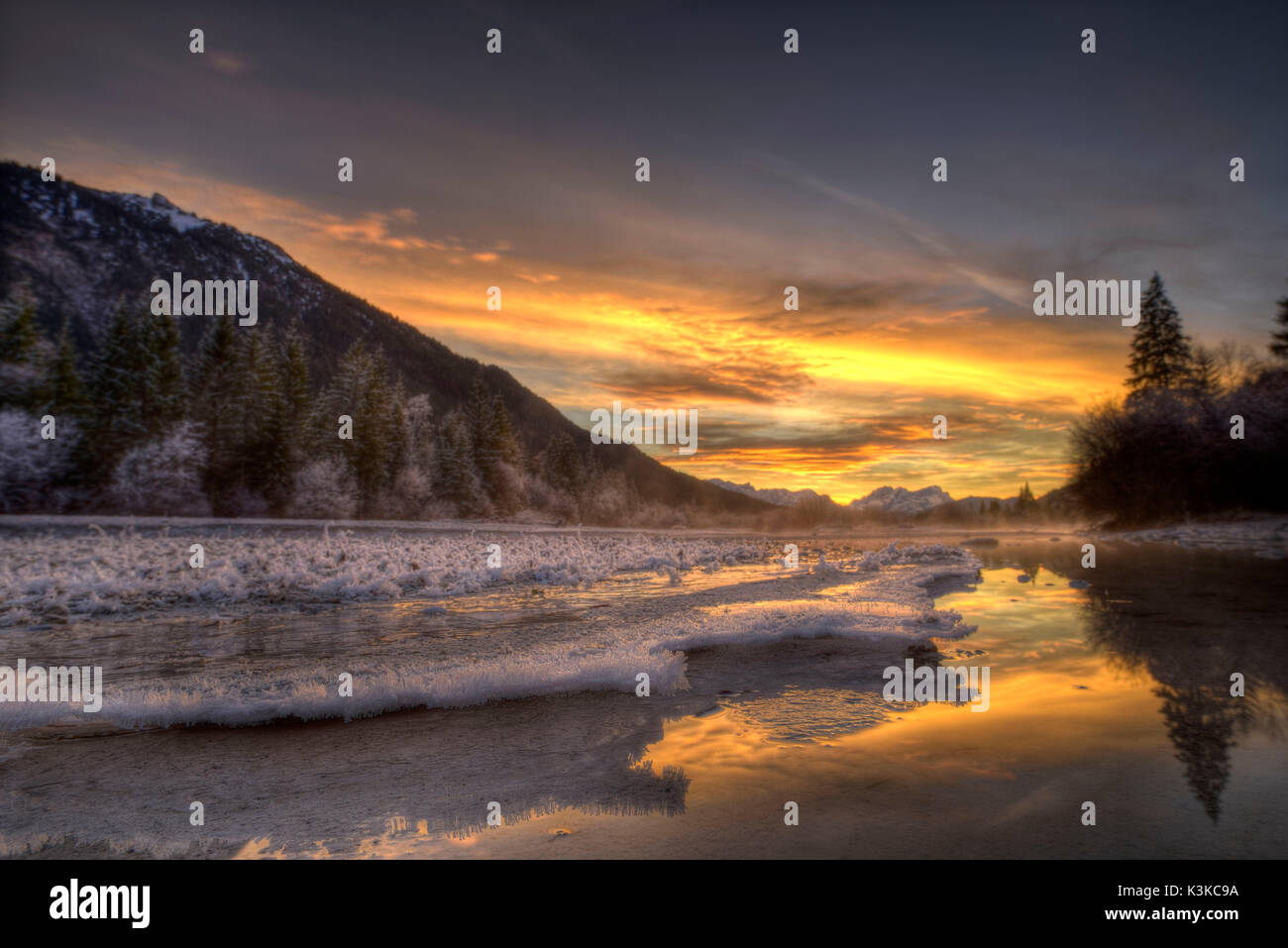 Spettacolare tramonto nell'Isar prati vicino a Wallgau. In primo piano belle strutture di ghiaccio, in background in distanza la gamma del Wetterstein con Zugspitze. Foto Stock