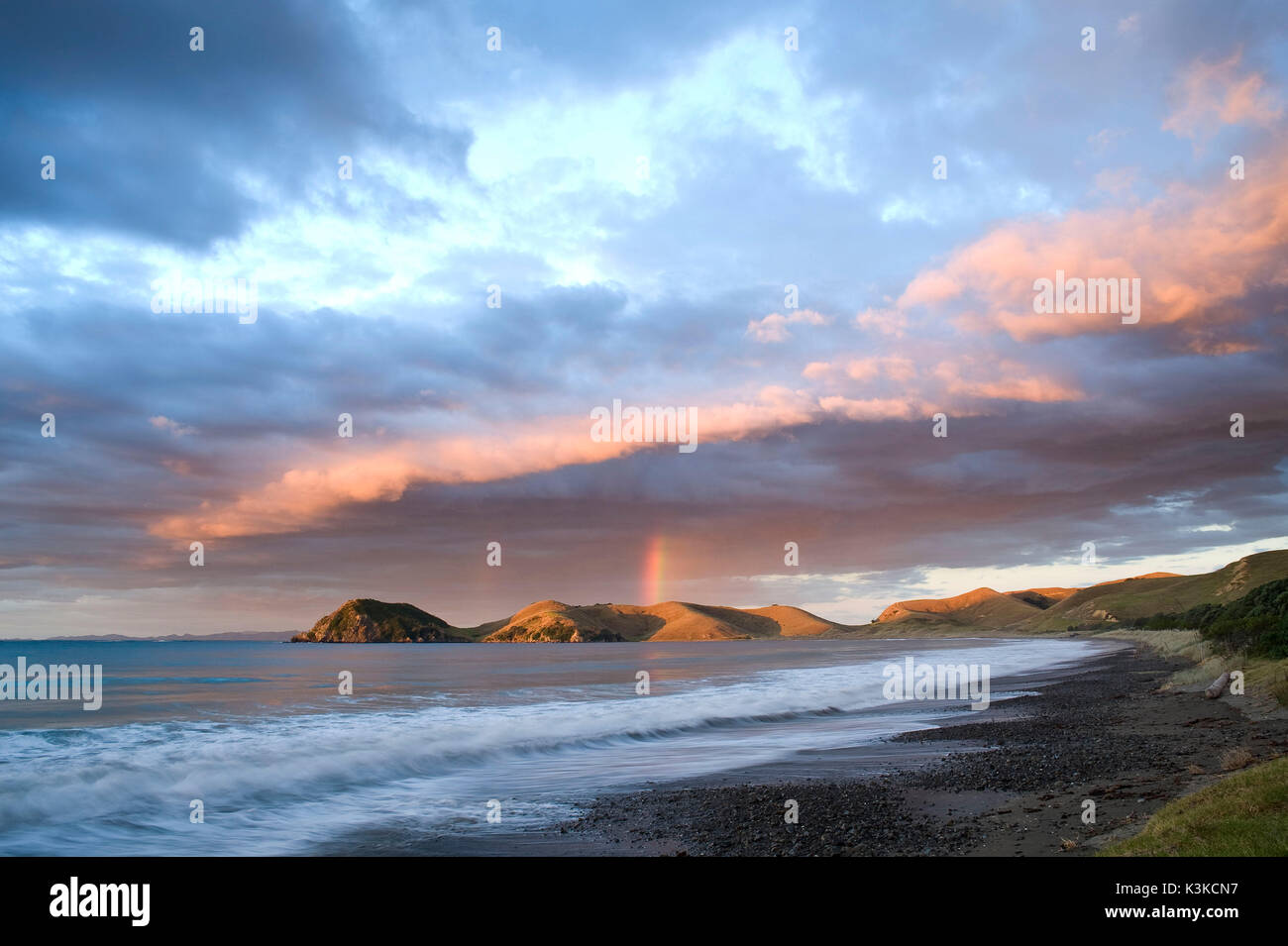 Drammatico tramonto con arcobaleno e la formazione di nube con port Jackson in Nuova Zelanda. Solitaria spiaggia in primo piano. Foto Stock