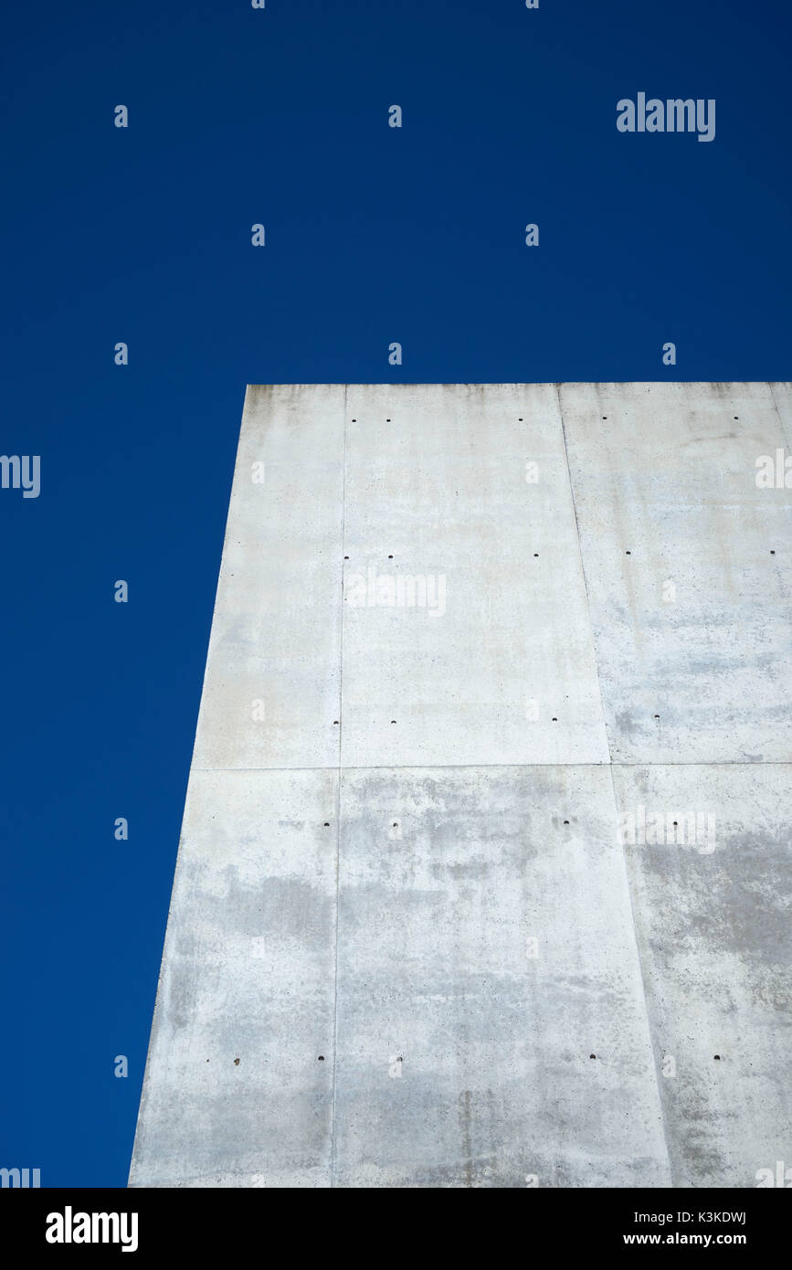 Calcestruzzo parete grigia con struttura e inclusioni come uno sfondo di fronte blu cielo privo di nuvole Foto Stock