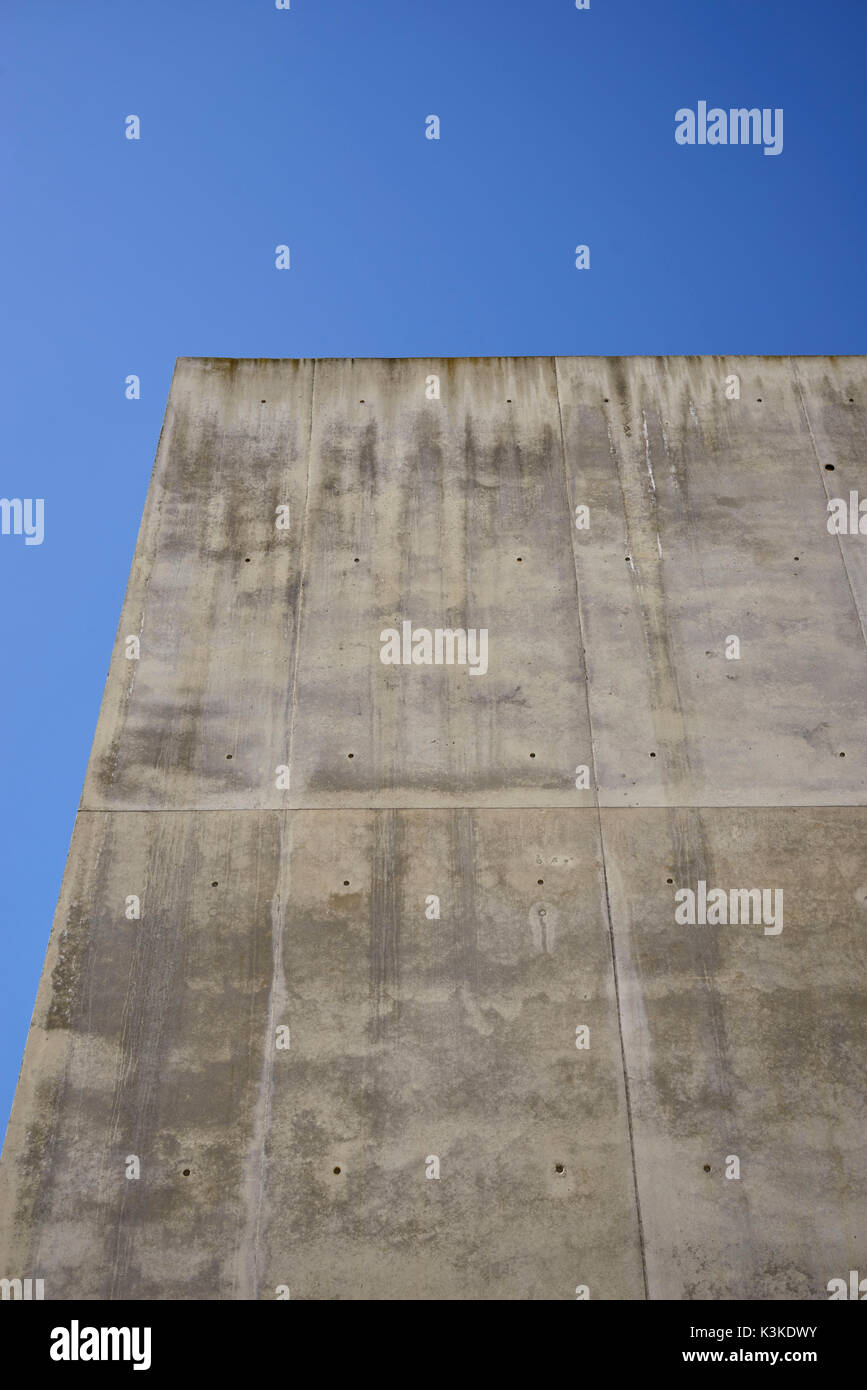 Calcestruzzo parete grigia con struttura e inclusioni come uno sfondo di fronte blu cielo privo di nuvole Foto Stock