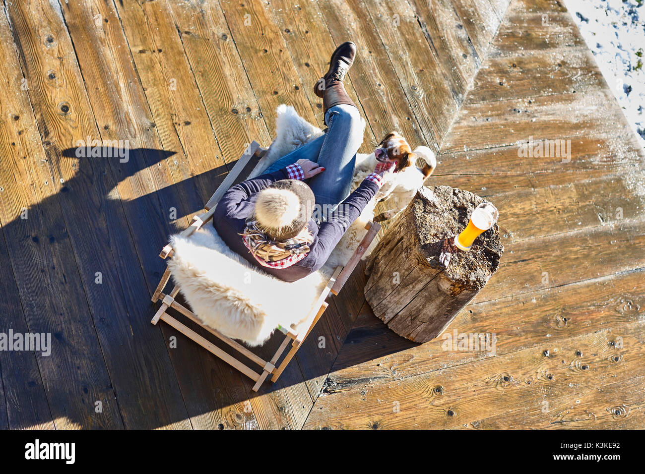 Una donna di mezza età, terrazza, sdraio, birra di grano, alp, capanna, cane, sedia a sdraio, inverno Foto Stock