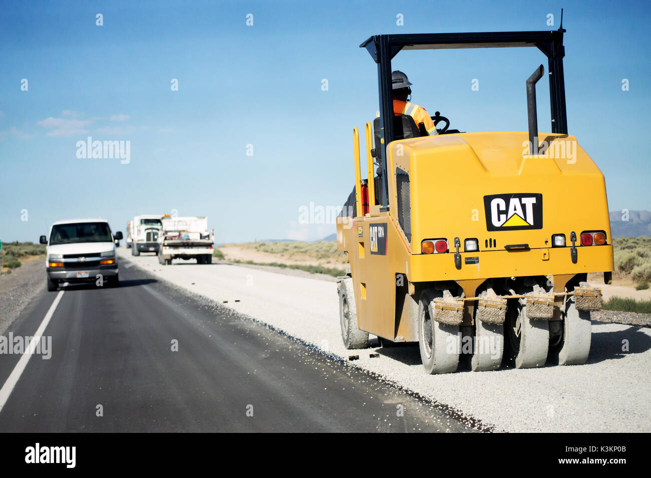 Un lavoratore edile di pilotaggio di un compattatore aspahlt resurfacing una strada nel deserto. Foto Stock