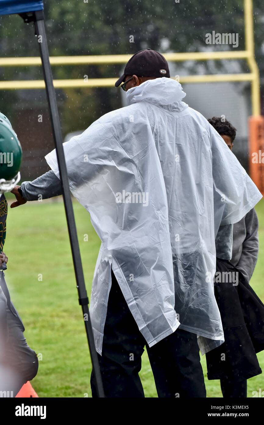 Allenatore di calcio che indossa il poncho al gioco delle piogge Foto Stock