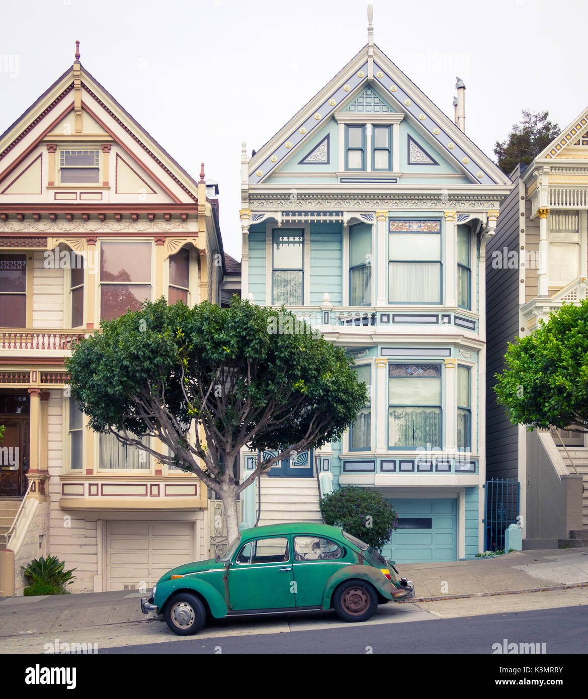 Un verde Volkswagen maggiolino parcheggiato di fronte alla "Painted Ladies' fila di case in stile vittoriano su Steiner Street (ad Alamo Square) a San Francisco. Foto Stock