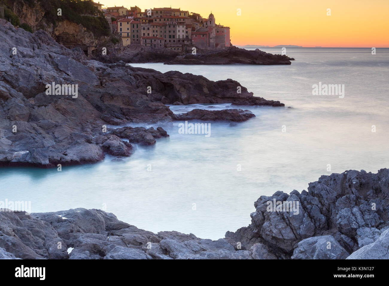 Sunrise sulle rocce di fronte alla piccola città di Tellaro, Lerici, Golfo di La Spezia, Liguria, Italia. Foto Stock