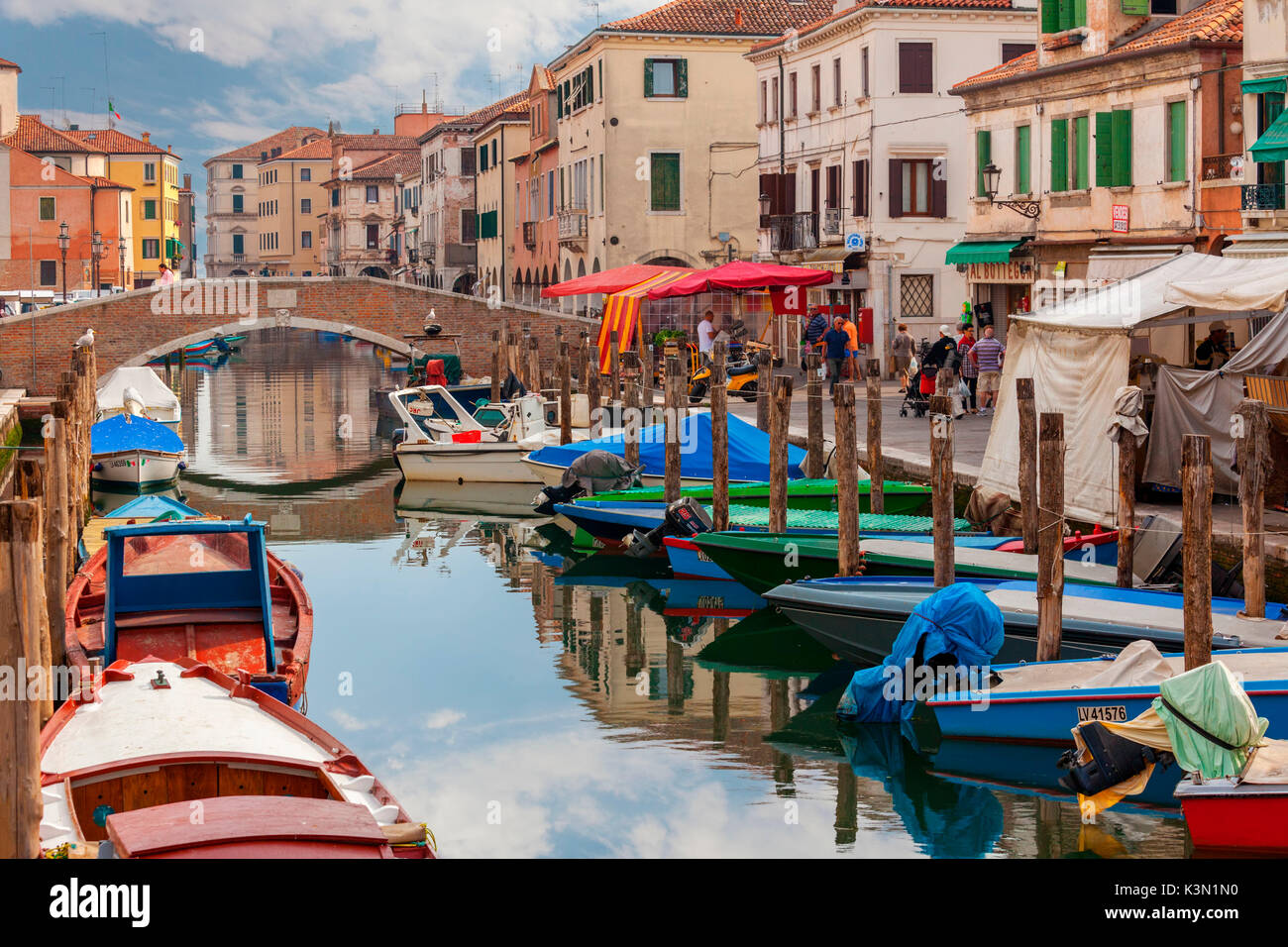 Chioggia. Barche ormeggiate nel canale e il mercato locale sulla strada. Veneto, Venezia, Italia Foto Stock