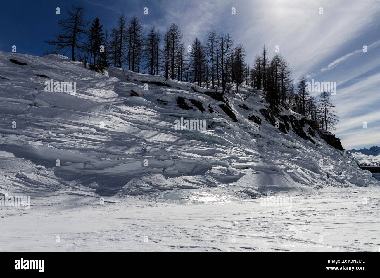 Collina coperta di neve e situato nel Lago di Devero, completamente congelato in inverno. Alpe Devero, Piemonte, Italia. Foto Stock
