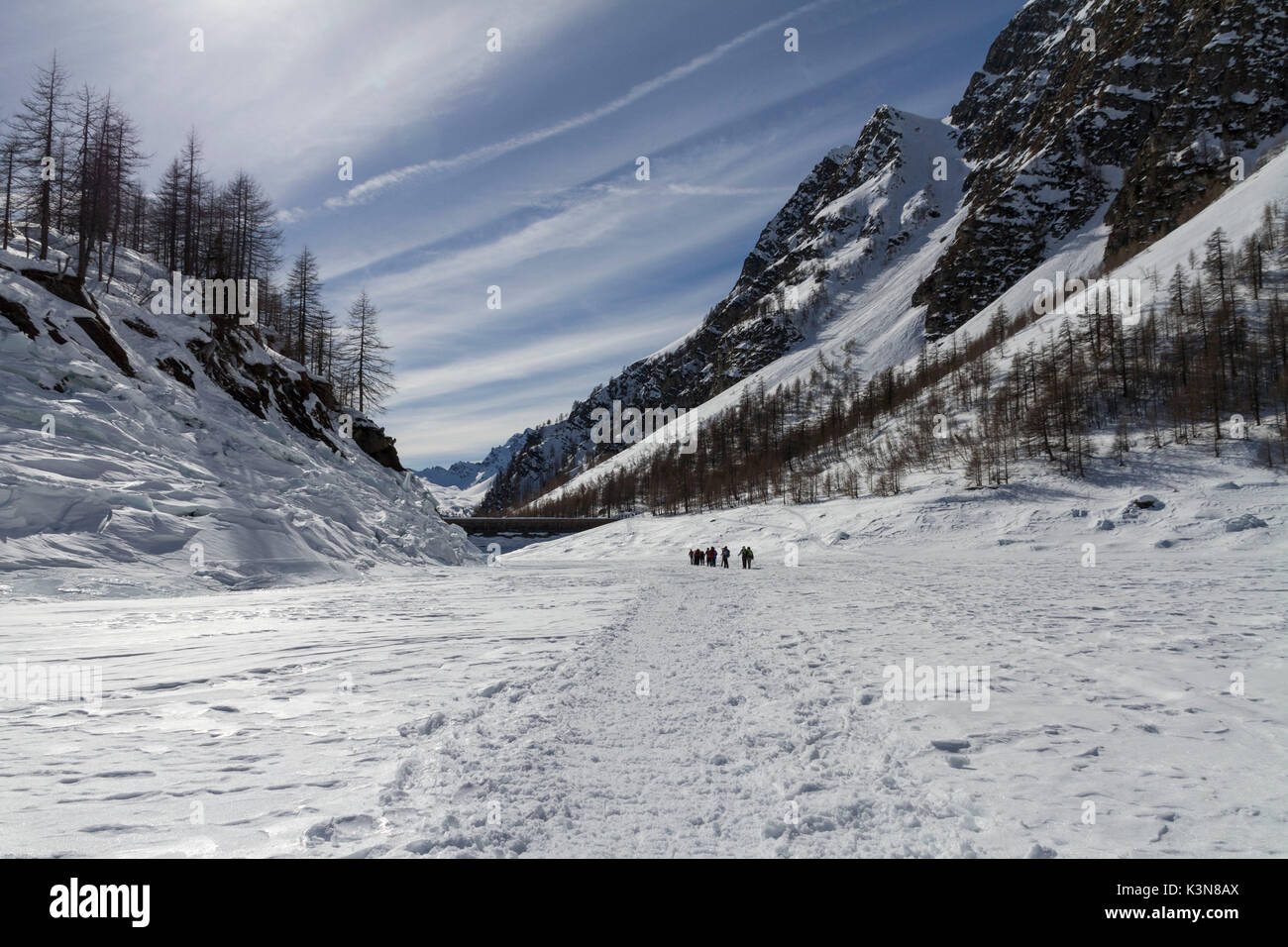 Alcuni escursionisti con racchette da neve passeggiate sulla neve congelata che copre il Lago di Devero, circondato di montagne in Alpe Devero parco naturale. Il Piemonte, Italia Foto Stock