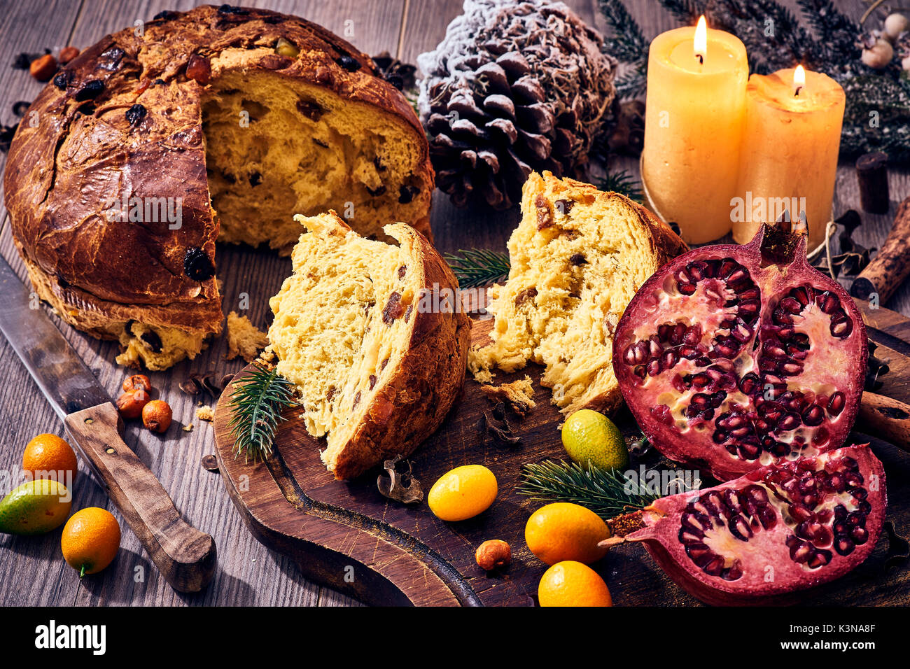 Italiano tradizionale torta di Natale con le candele, melograno e frutti invernali, panettone Foto Stock