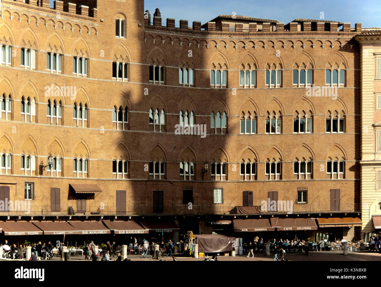 L ombra della Torre del Mangia è proiettato sulle facciate di antichi edifici che circondano la Piazza del Campo a Siena, Toscana, Italia Foto Stock