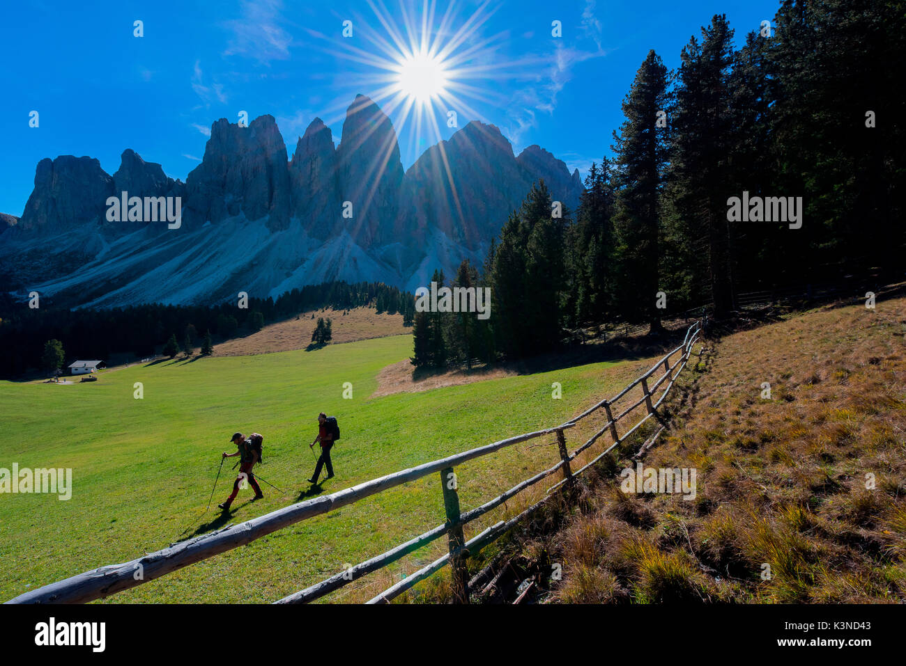 Odle,Funes, Dolomiti,Trentino Alto Adige, Italia due escursionisti fotografato mentre essi passano attraverso la valle al di sotto delle Odle. In primo piano una recinzione Foto Stock