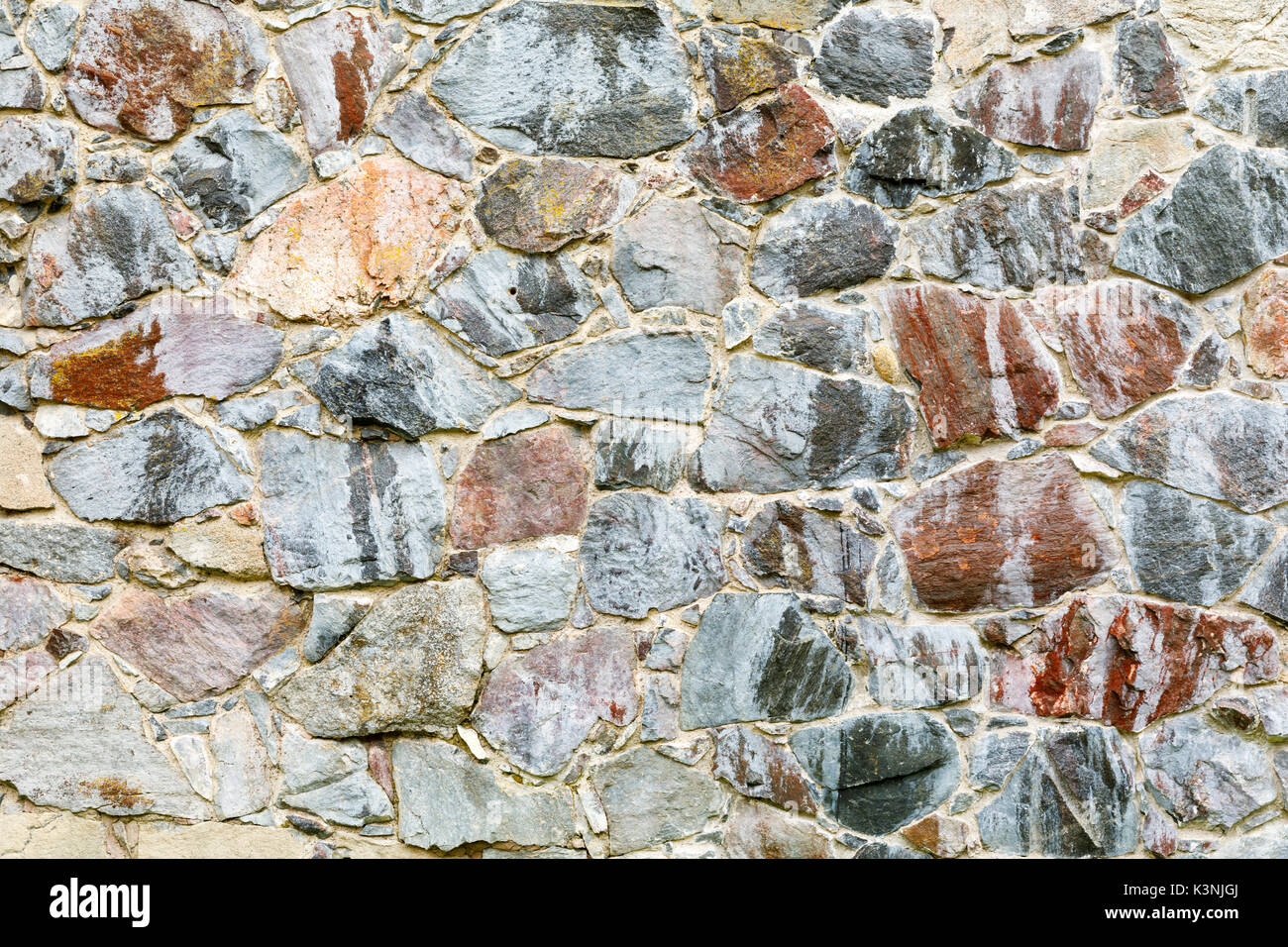 Sullo sfondo di un muro fatto di vecchi round pietre di terra Foto Stock