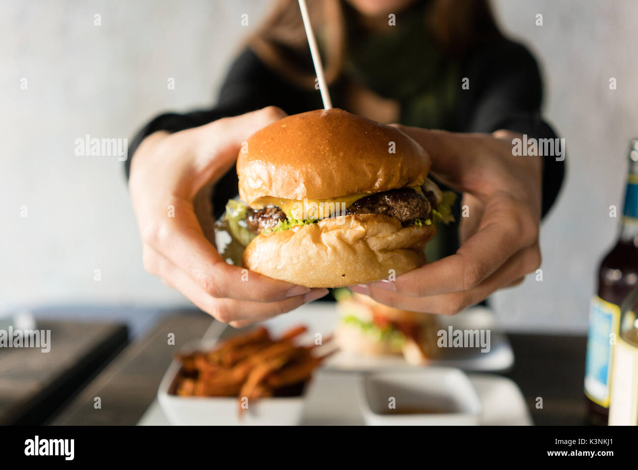 La donna a mangiare cheeseburger sandwich nel ristorante Foto Stock