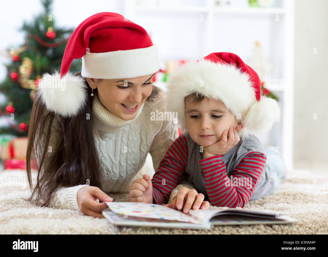 Ragazzo del bambino e la sua mamma la lettura di libro a Natale Foto Stock