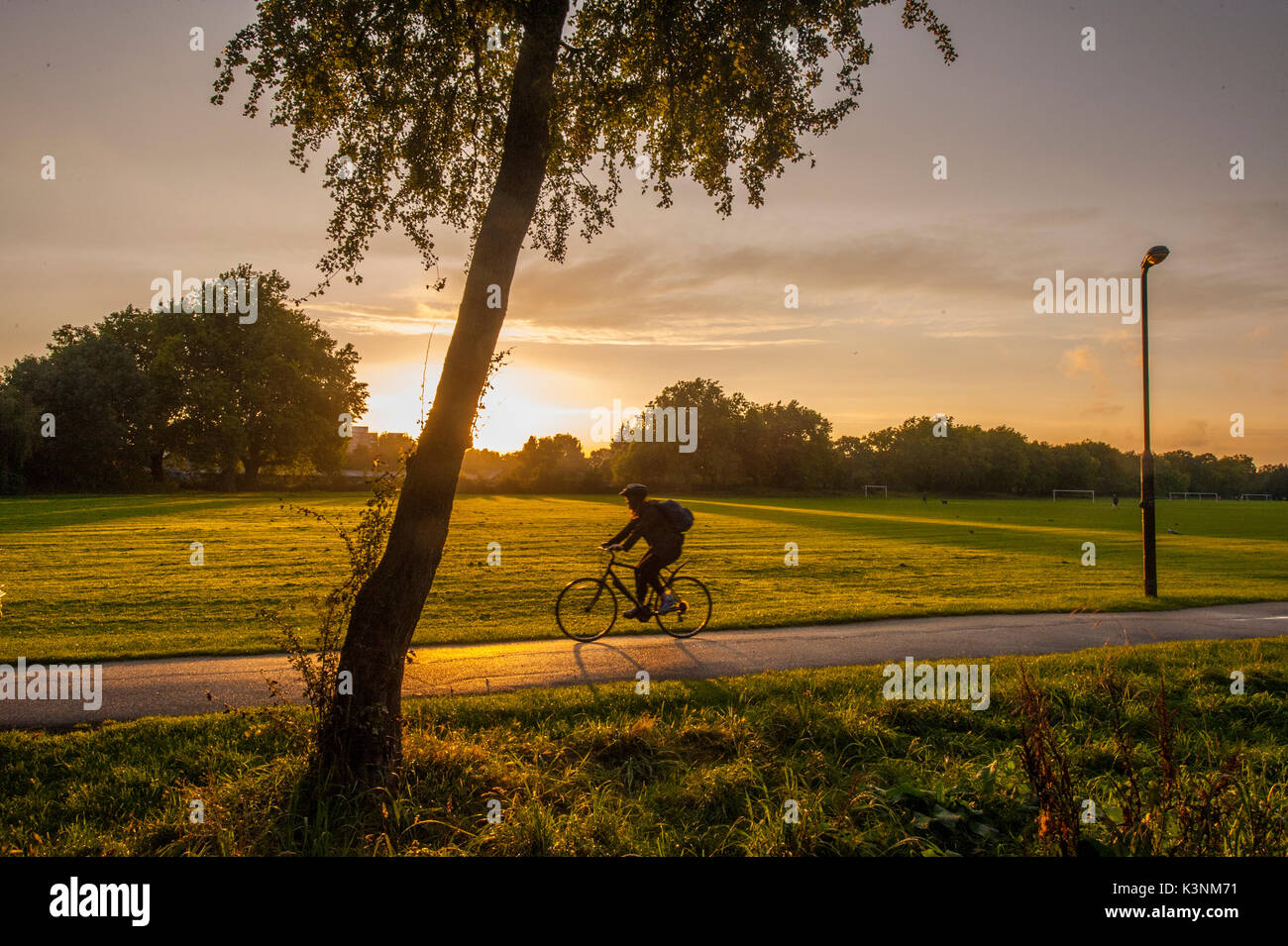 Un uomo di cicli a casa dopo il lavoro in un parco di Londra Foto Stock