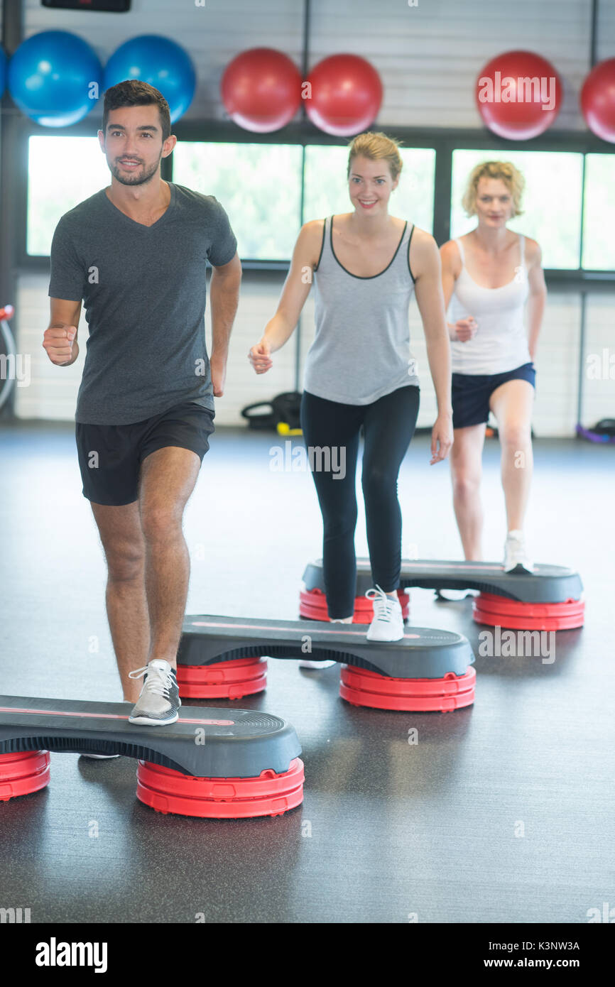 Lavoro di gruppo con pesi e stepper in palestra Foto Stock