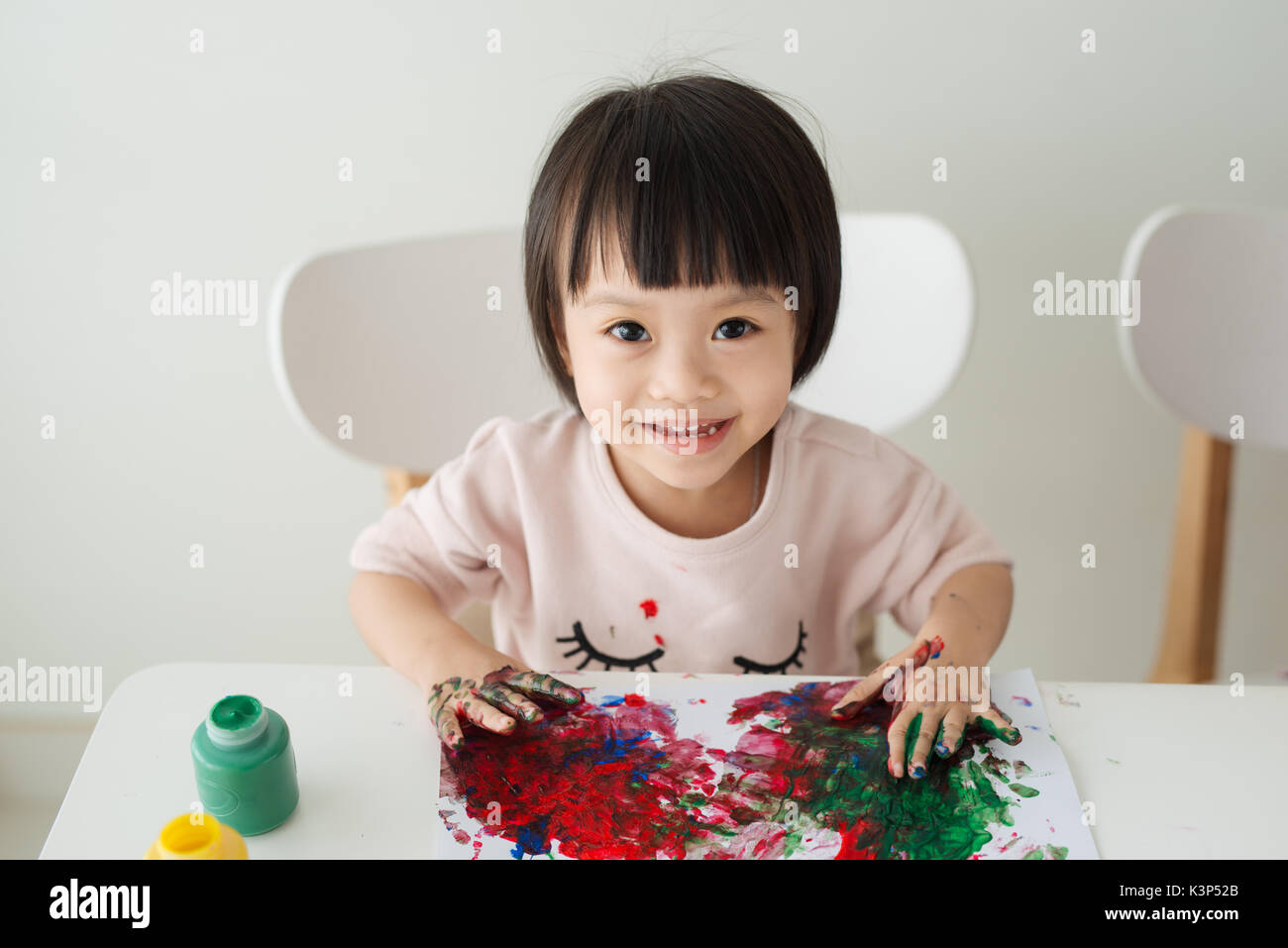 Poco ragazza asiatica pittura con pennello e vernici colorate Foto Stock