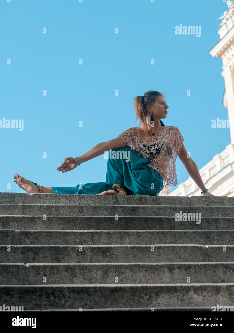 Donna con la meditazione sulla parte superiore della scala di città in  background. Giovane ragazza in pantaloni alladin fare yoga nella città Foto  stock - Alamy