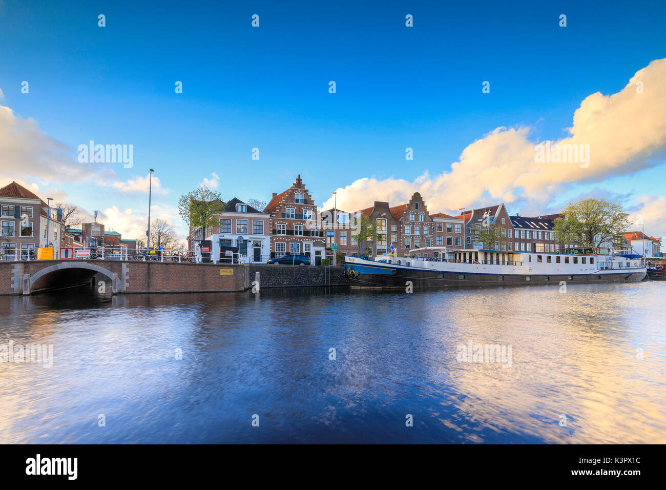 Cielo blu e nuvole sul case tipiche riflessa nel canale del fiume Spaarne Haarlem Olanda settentrionale dei Paesi Bassi in Europa Foto Stock