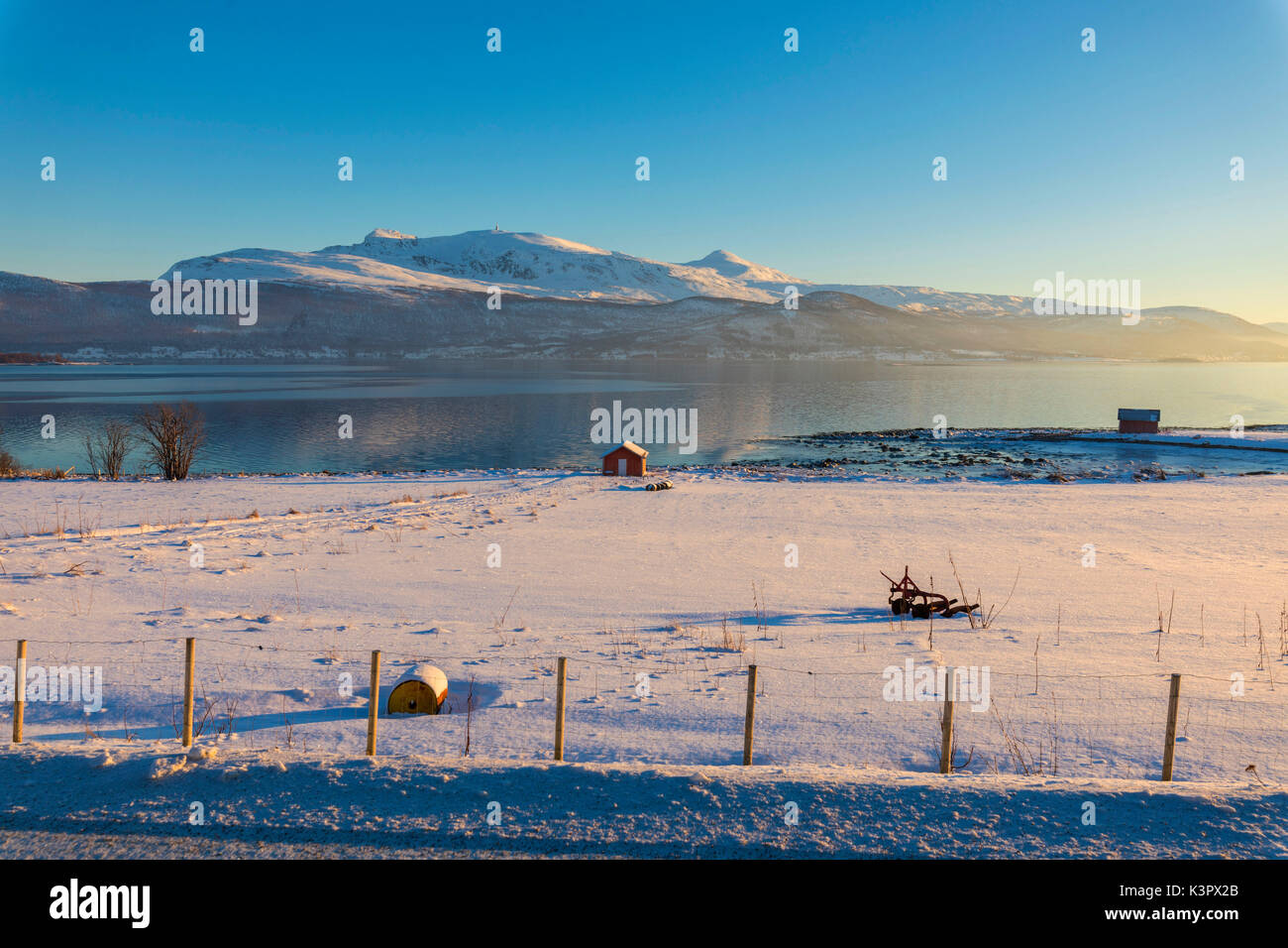 Capanna in legno nel paesaggio innevato rivolta verso il mare a freddo sulla strada che conduce da Gibostad a Finnsnes Senja Tromsø Norvegia Europa Foto Stock