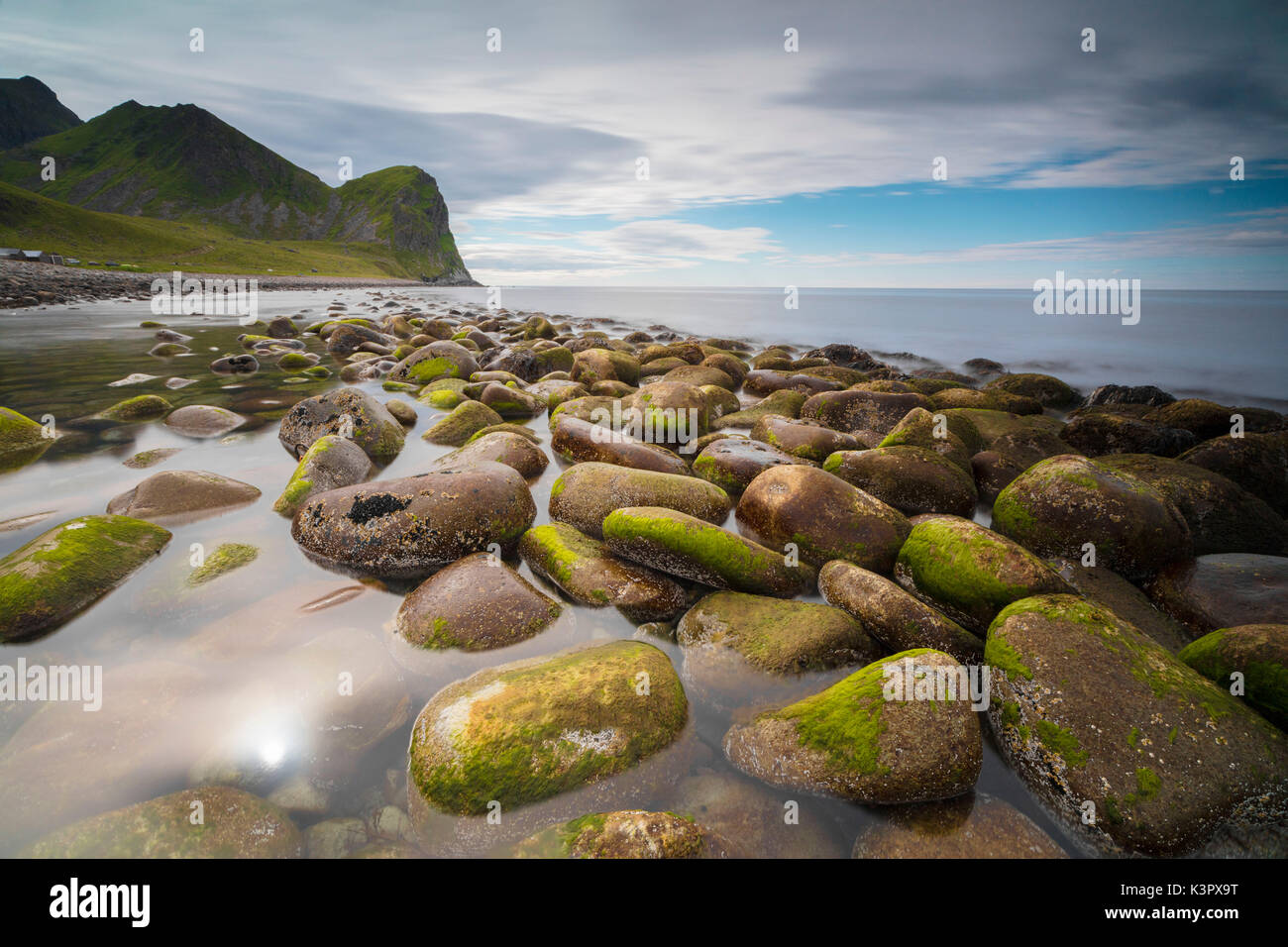 Rocce sulla spiaggia fotogramma il calmo mare chiaro Vestvagøy Unstad Isole Lofoten in Norvegia Europa Foto Stock