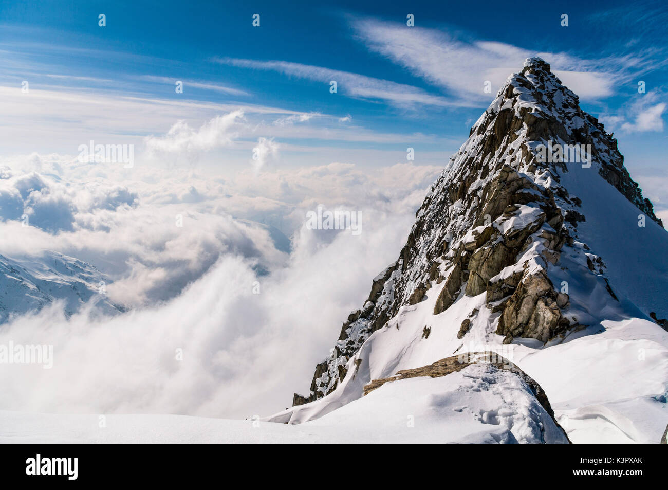Cima della montagna sopra le nuvole, gruppo Mittagorn, Vallese, Svizzera Foto Stock