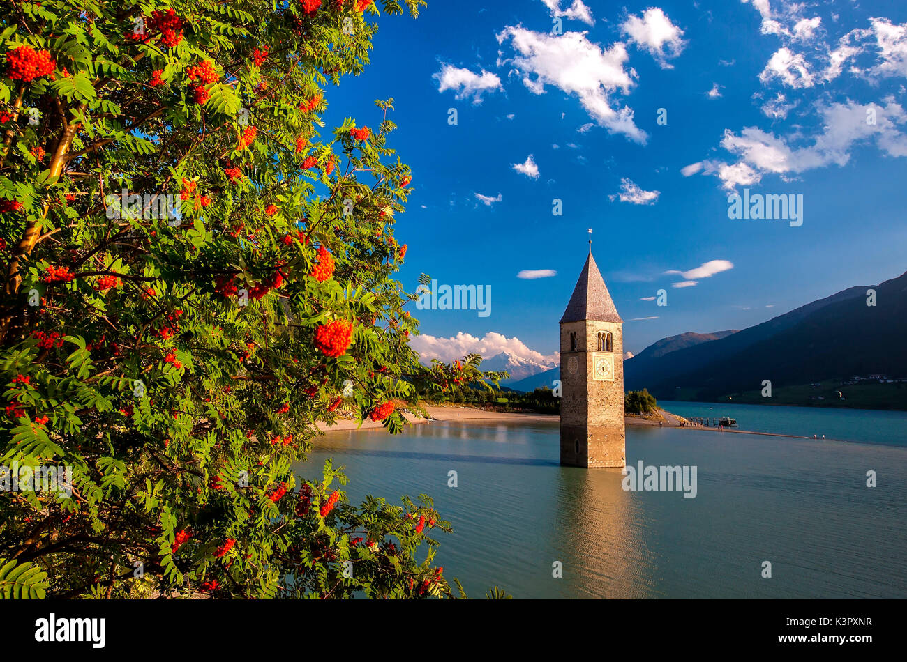 Il lago di Resia è un lago artificiale nella porzione occidentale dell Alto Adige, Italia, circa 2 km (1 miglia) a sud del Passo Resia, che forma il confine con l'Austria, e a 3 km ad est del crinale del monte formando il confine con la Svizzera. Con la sua capacità di 120 milioni di metri cubi (97.000 ft) è il più grande lago della provincia. La sua area superficiale di 6,6 km lo rende anche il più grande lago al di sopra di 1.000 m nelle Alpi. Esso è alimentato dall'Adige, Rojenbach e Karlinbach e svuotato dall'Adige. Foto Stock