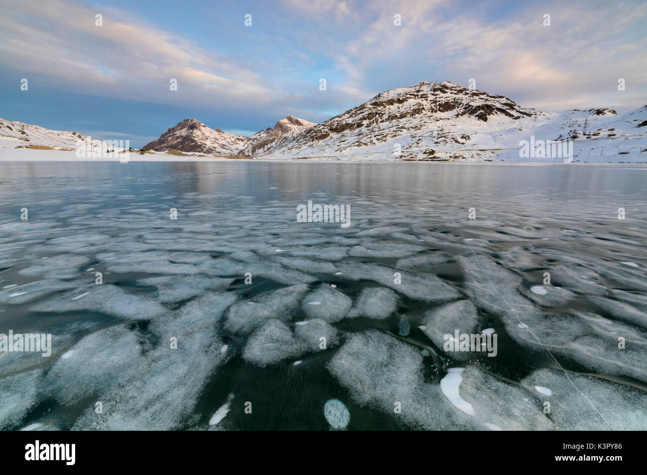 La superficie ghiacciata del Lago Bianco incorniciato da vette innevate del Bernina cantone dei Grigioni Engadina Svizzera Europa Foto Stock