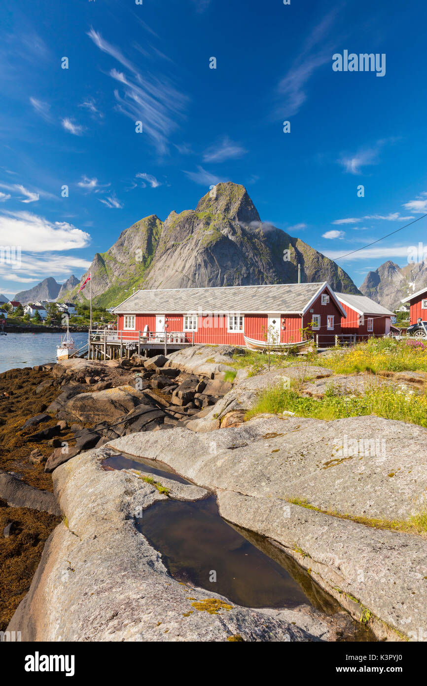 Tipiche case di pescatori chiamato Rorbu incorniciato da picchi rocciosi e mare blu Reine Moskenes Isole Lofoten in Norvegia Europa Foto Stock