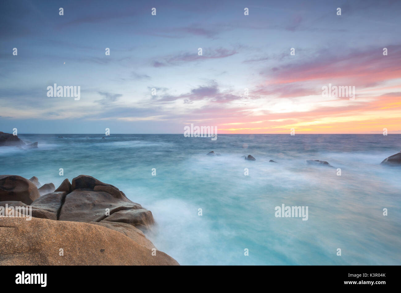 Il Fiery sky telai le onde che si infrangono sulle rocce di Capo Testa a Santa Teresa di Gallura in provincia di Sassari Sardegna Italia Europa Foto Stock