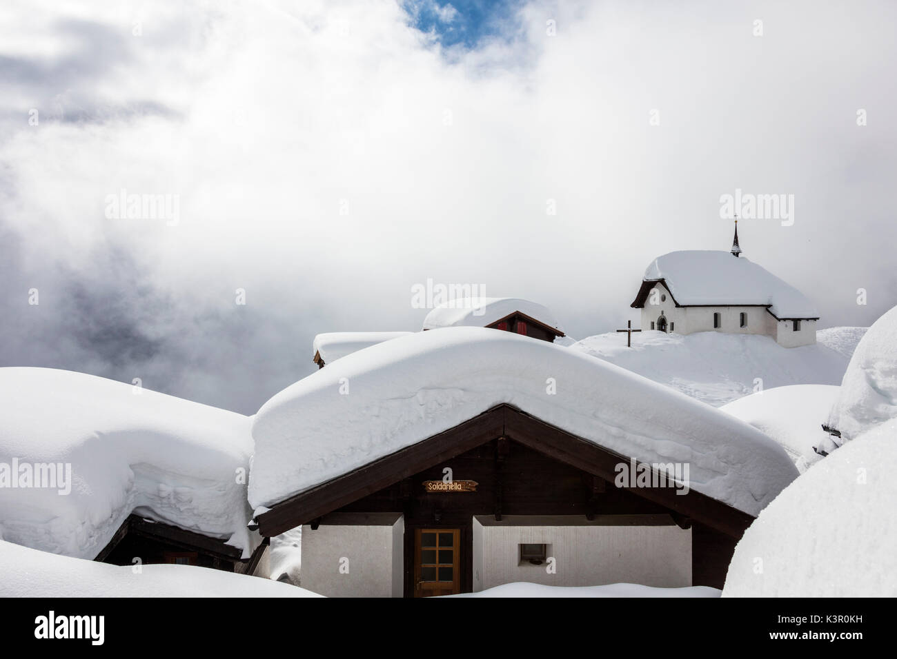 Coperta di neve rifugi di montagna e chiesa circondato da nuvole basse Bettmeralp distretto di Raron nel canton Vallese Svizzera Europa Foto Stock