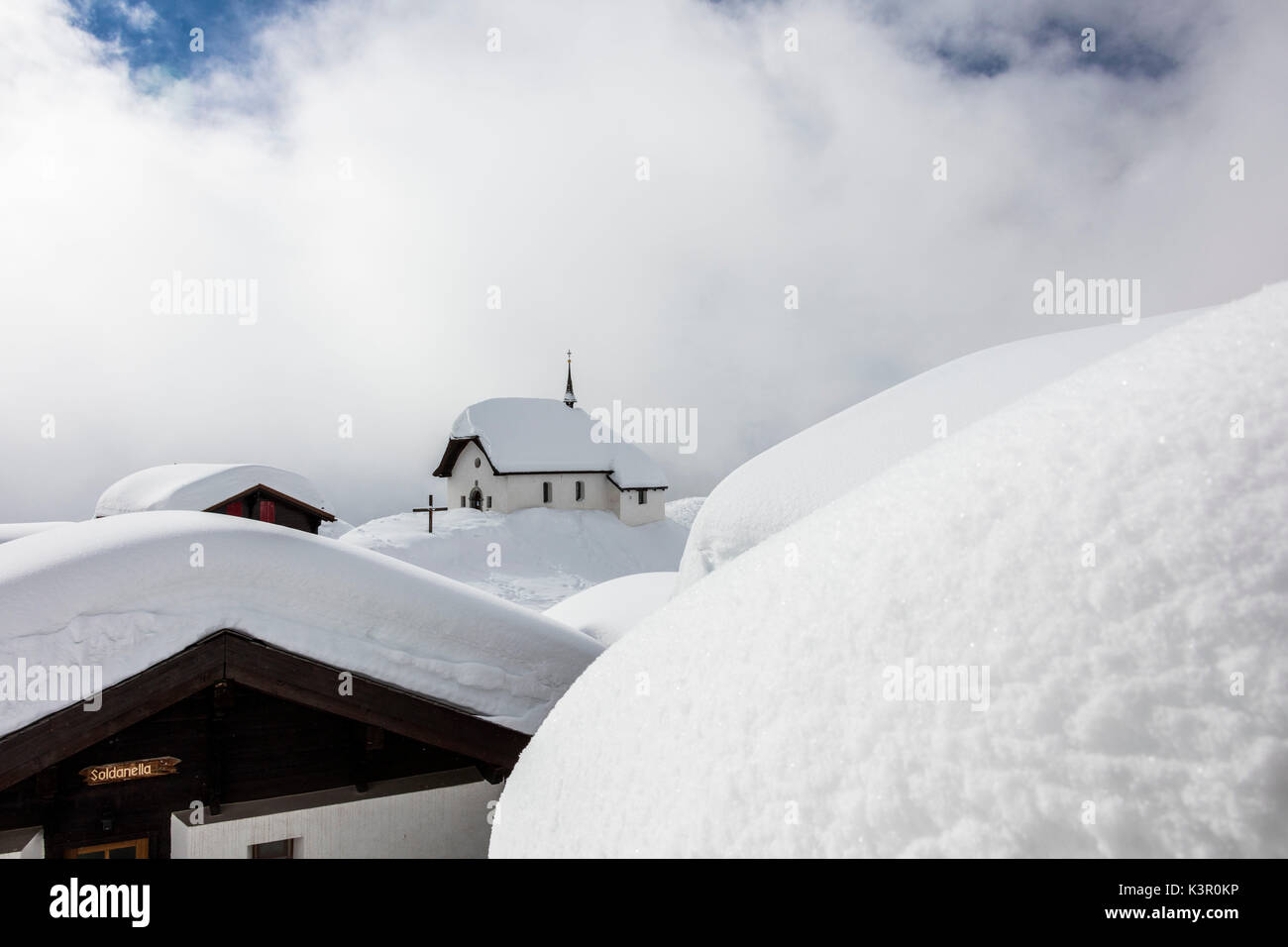 Telaio di nuvole i rifugi di montagna e chiesa con neve Bettmeralp distretto di Raron nel canton Vallese Svizzera Europa Foto Stock