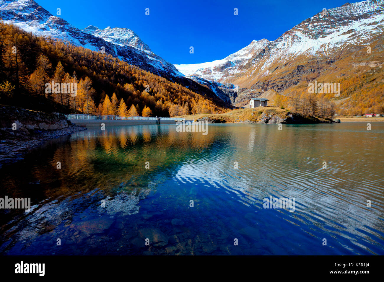 Riflessi nel lago blu di Alp Grum in autunno. Sullo sfondo le cime innevate e sul ghiacciaio Palù. Valle di Poschiavo Canton Grigioni Svizzera Europa Foto Stock