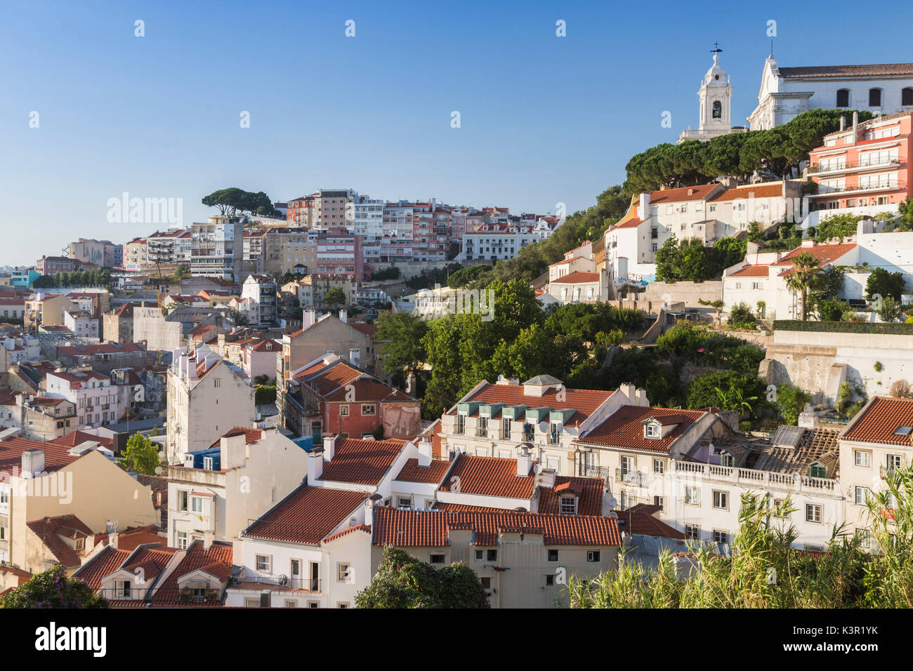 Vista di un quartiere residenziale di Lisbona circondato da alberi e la chiesa sotto un cielo di estate blu Portogallo Europa Foto Stock
