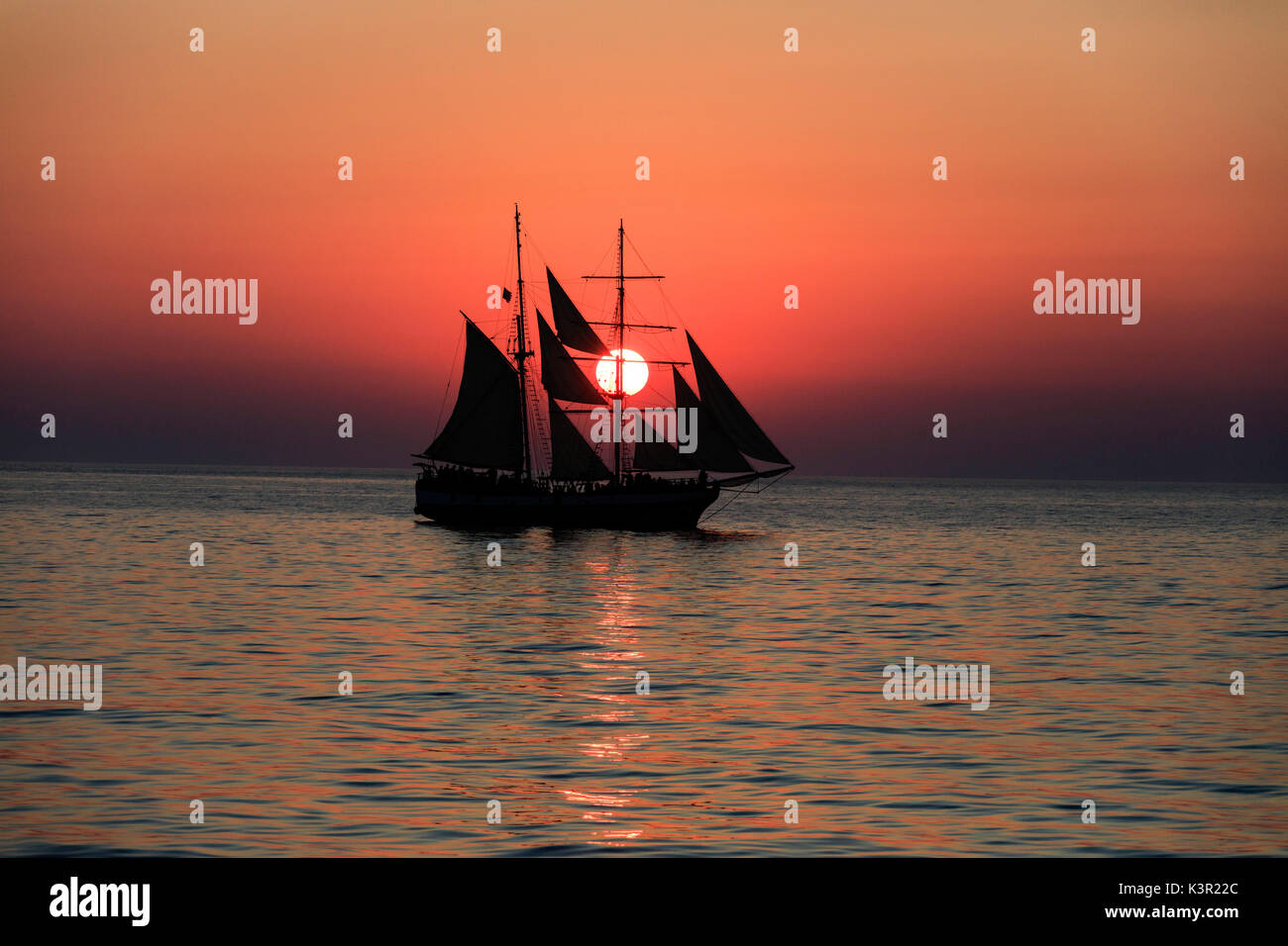 Un veliero nel Mare Egeo mentre il sole tramonta Santorini Cyclades Grecia Europa Foto Stock