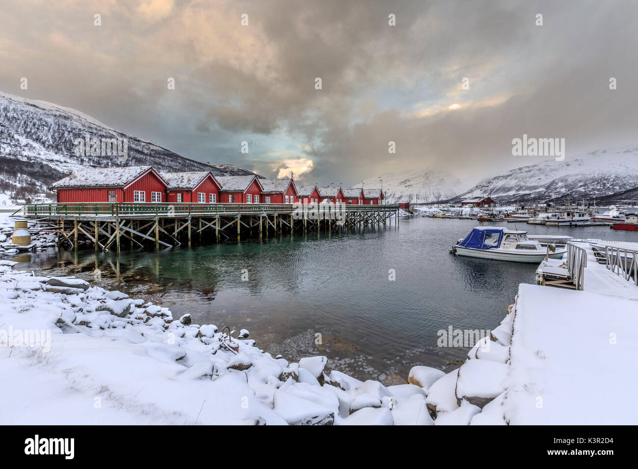 Rosso tipiche baite in legno dei pescatori in presenza di neve e ghiaccio paesaggio delle Alpi Lyngen Tromsø Lapponia Norvegia Europa Foto Stock