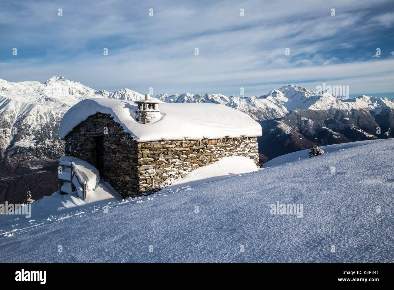Coperta di neve rifugio dopo una nevicata in background Val Masino Olano Valtellina Alpi Retiche Lombardia Italia Europa Foto Stock